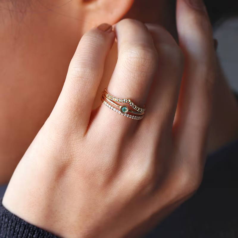 A close-up of a hand wearing a decorative ring near an ear.