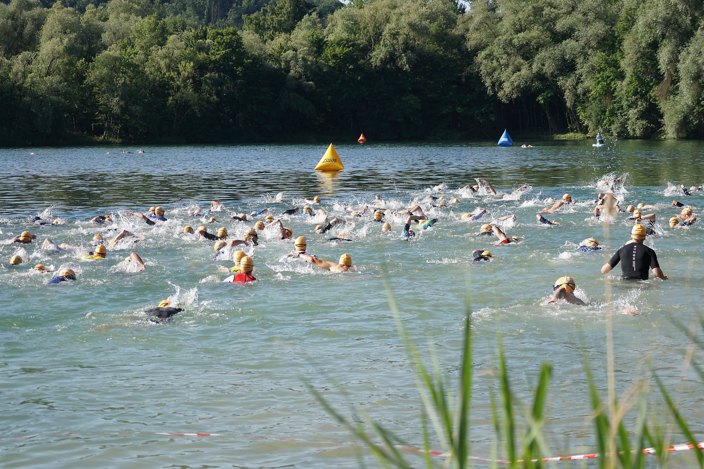 Mehrere Triathleten legen die Schwimmdistanz in einem See zurück.