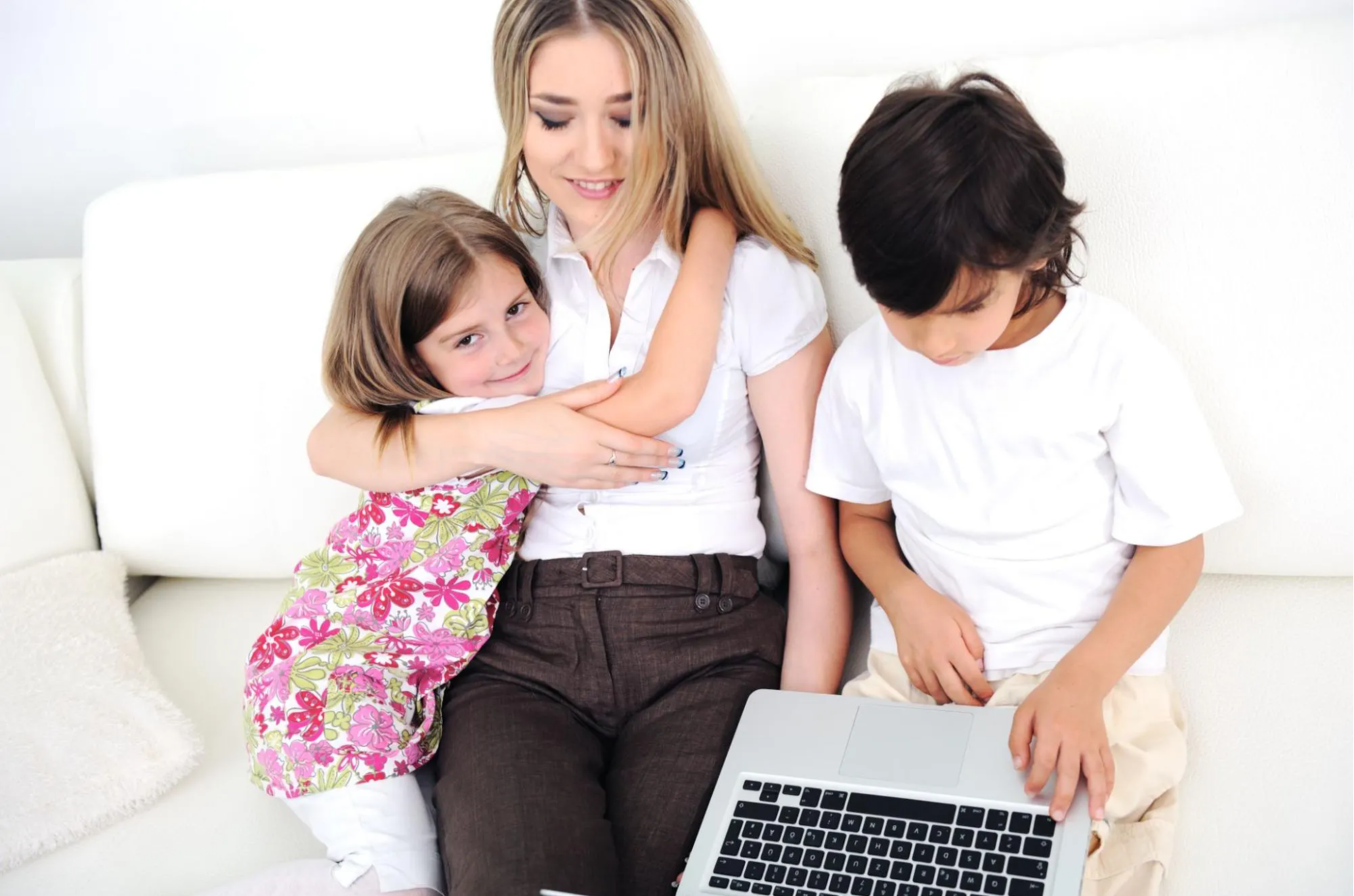 Mother on the couch with laptop and 2 kids 