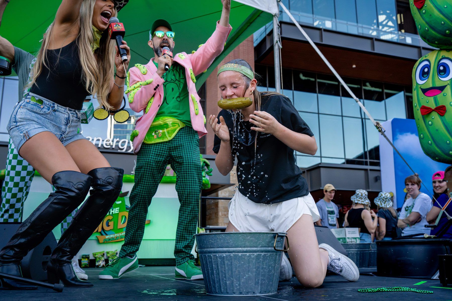 Contestant bobbing for pickles on the main stage at The Big Dill World's Largest Pickle Party Arlington Texas 2025.