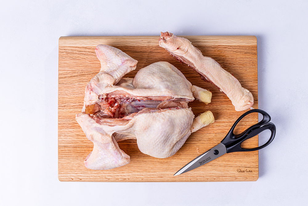 Raw chicken pieces on a Classic Chopping Board with Signature Scissors.