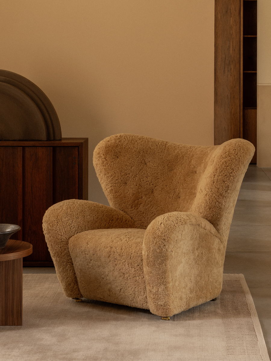 A cozy, beige upholstered armchair in a modern interior setting.