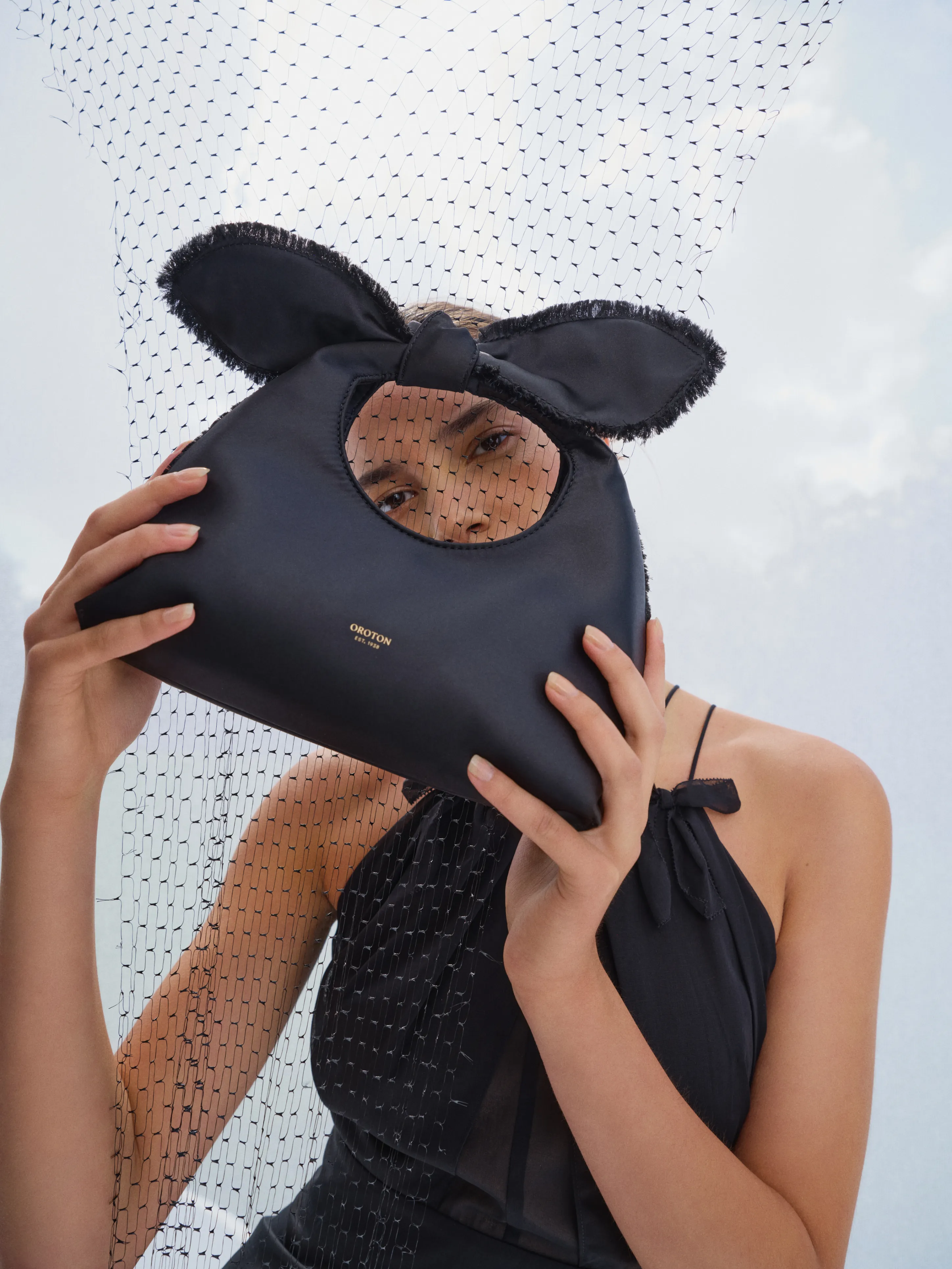 A person holding a black bag with bunny ears against a light background.