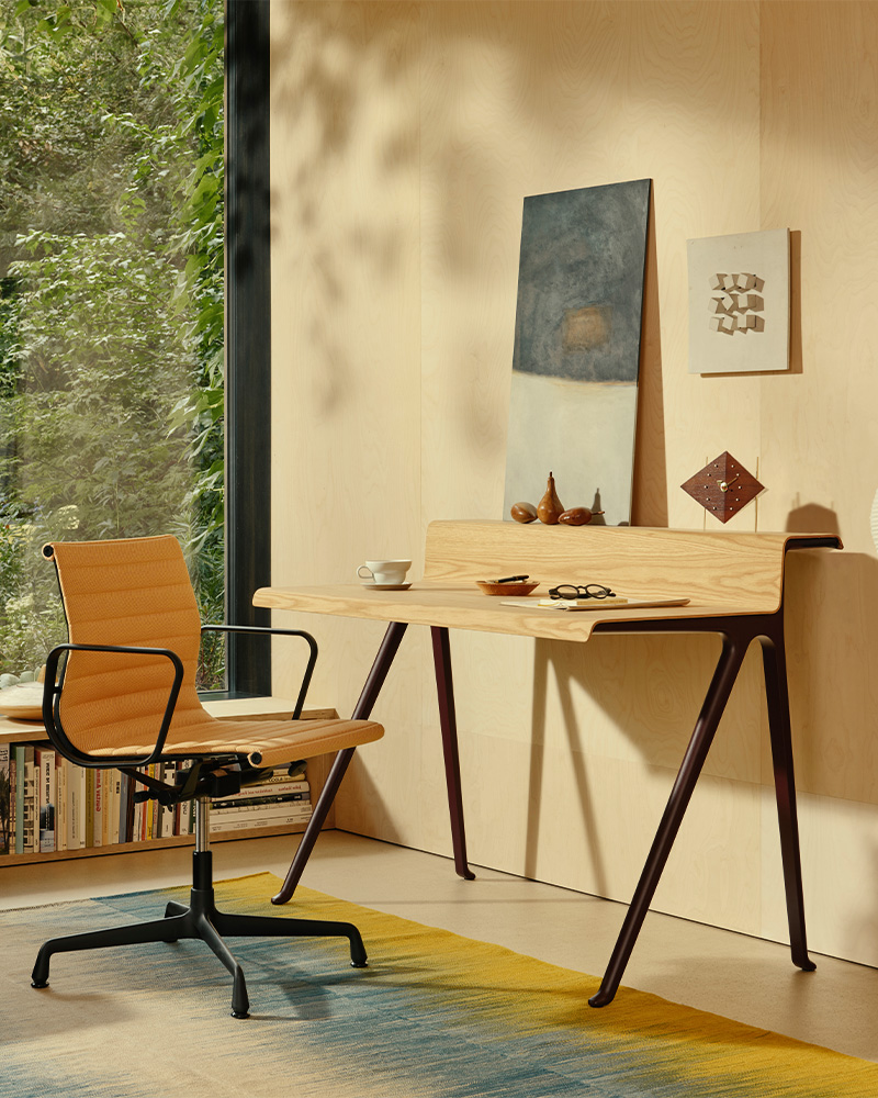 A modern Vitra EA chair with a brown seat and white armrests.