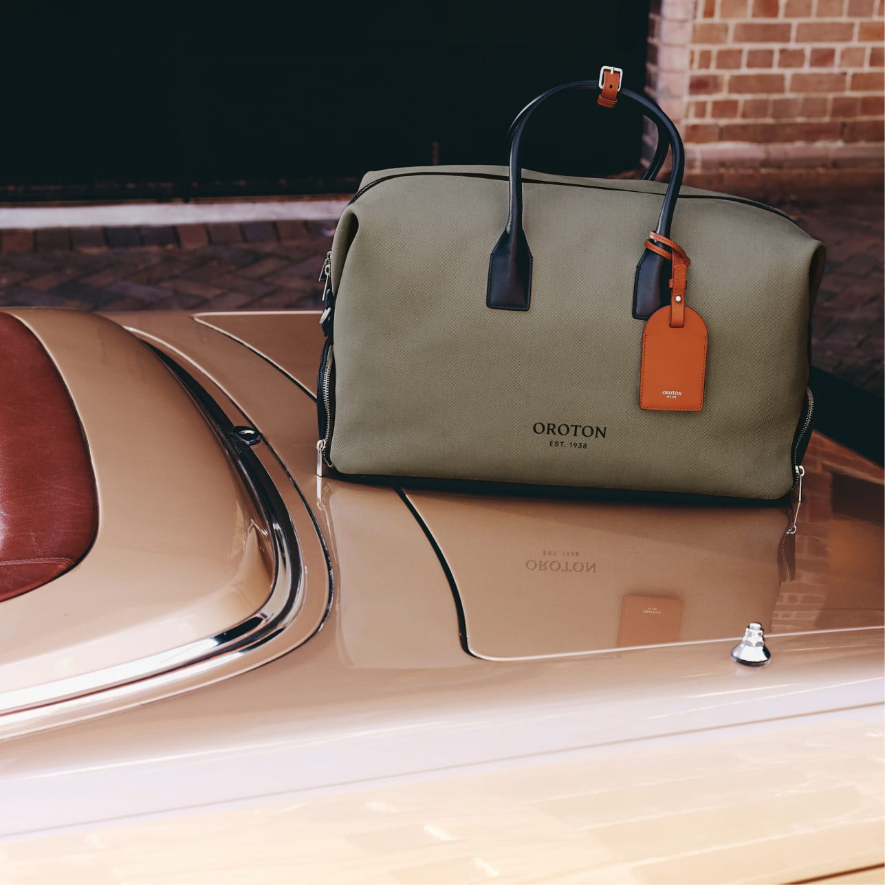 A green bag with leather accents on a car's trunk.