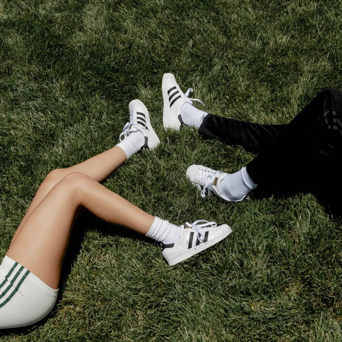 top view of male and female models wearing adidas superstar sneakers