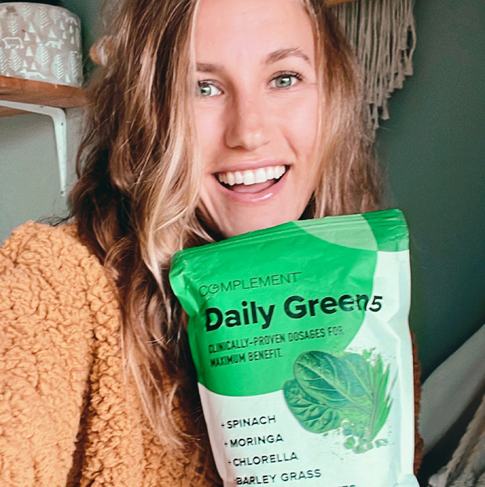 young woman holding a pouch of daily greens