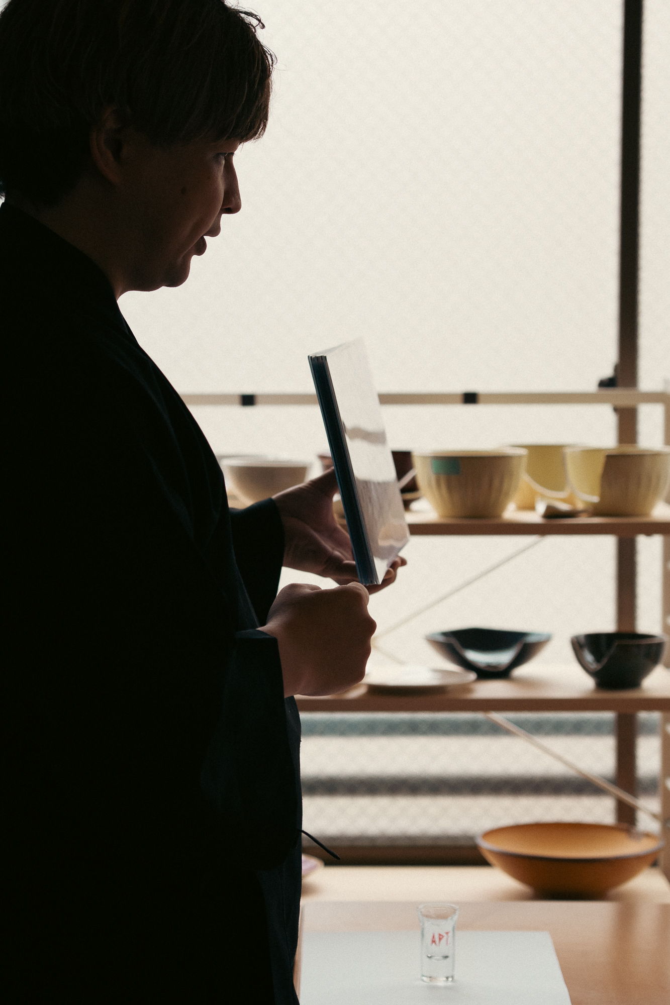 Person holding a mirror in front of shelves with various bowls.