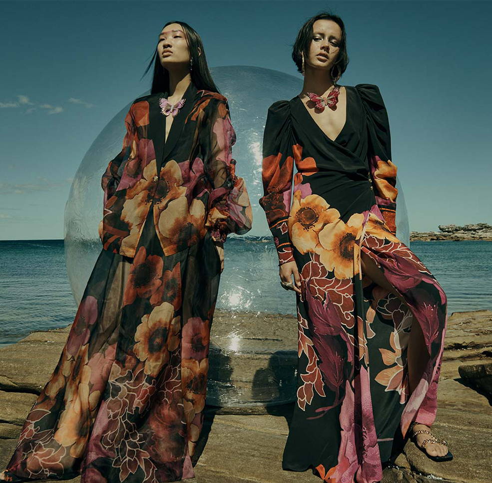 two models wearing CAMILLA midnight poppy black and pink orange floral printed outfits