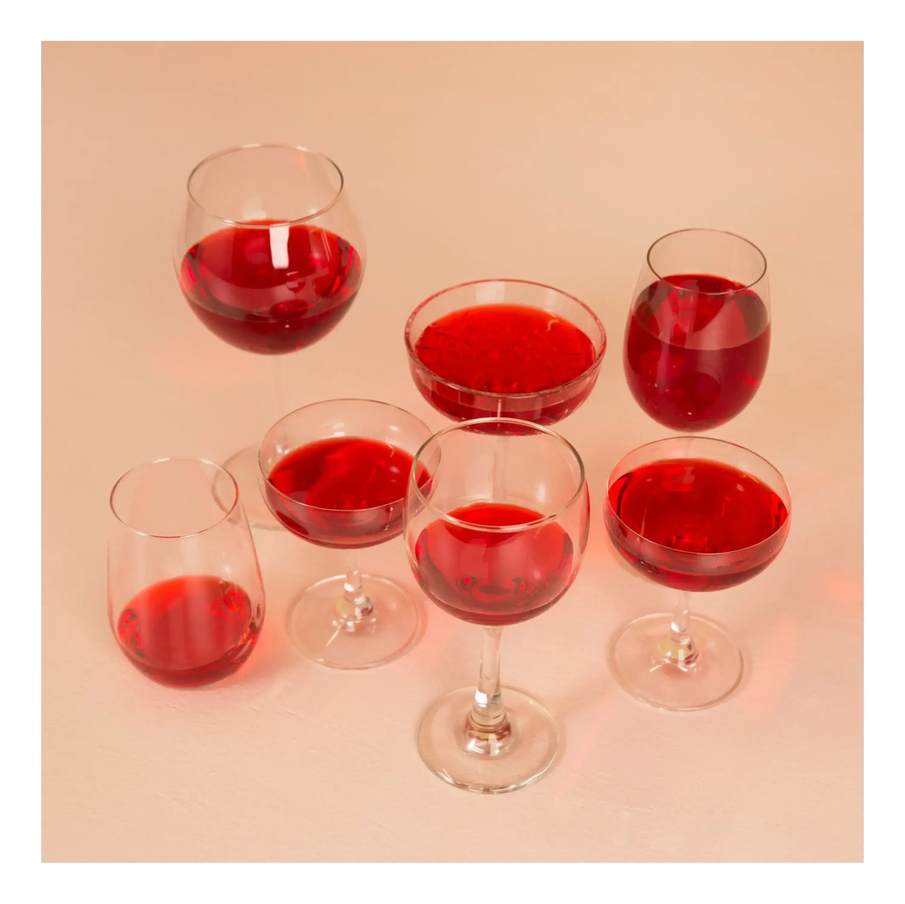 Seis taças e um copo contendo liquido de cor vermelha