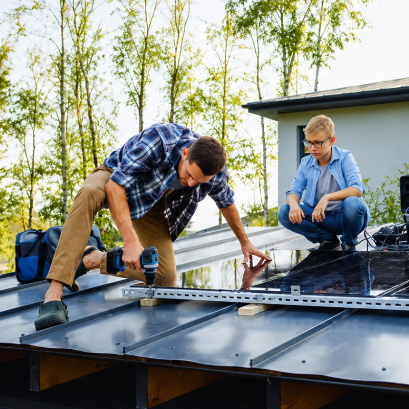 Father and son installing solar panels on a roof.