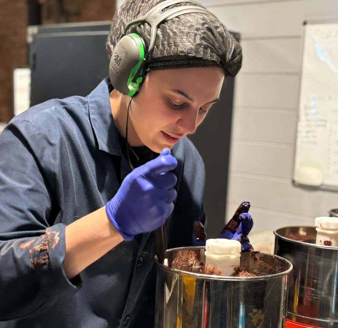 Person in protective gear working with materials in a laboratory setting.