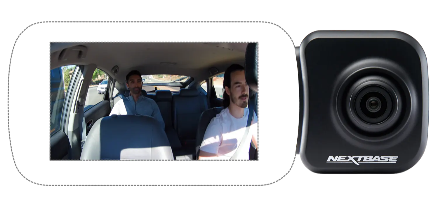 Two men seated inside a car, with a camera display.