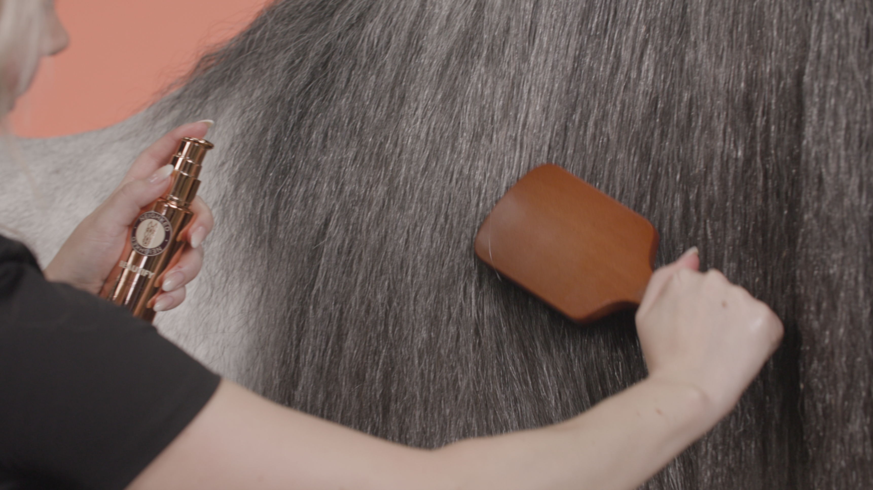 Person grooming a horse's mane with a brush and BEAUTIFY oil.