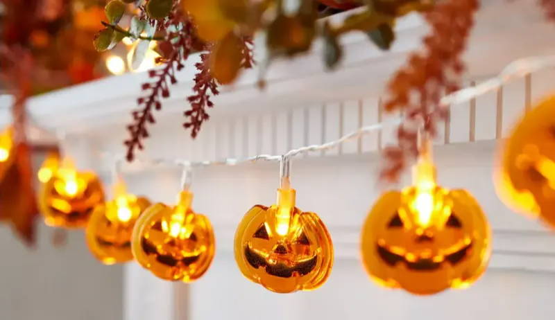 Illuminated Halloween pumpkin fairy lights draped along mantel