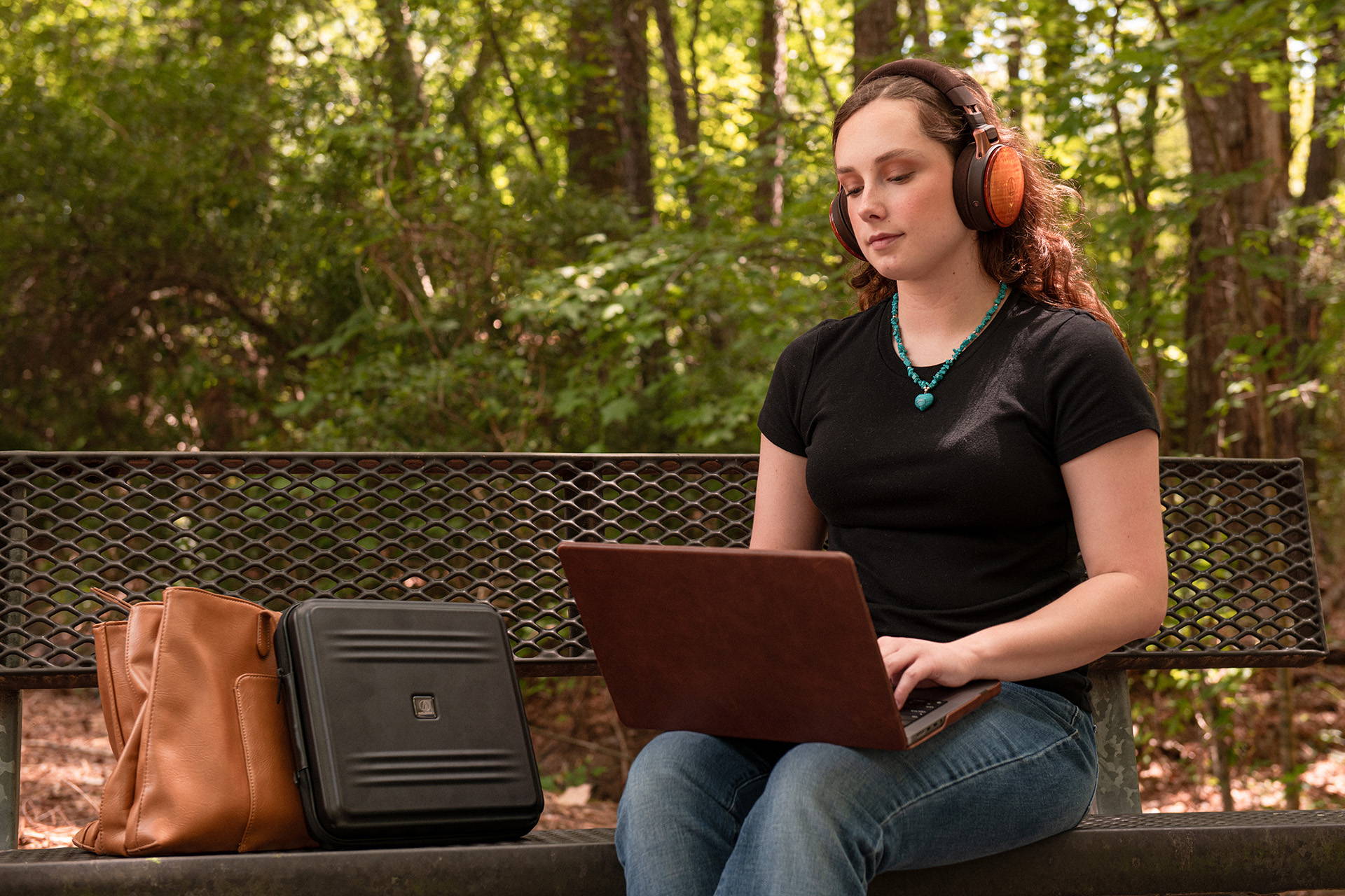 woman listening to music on laptop sitting on a bench