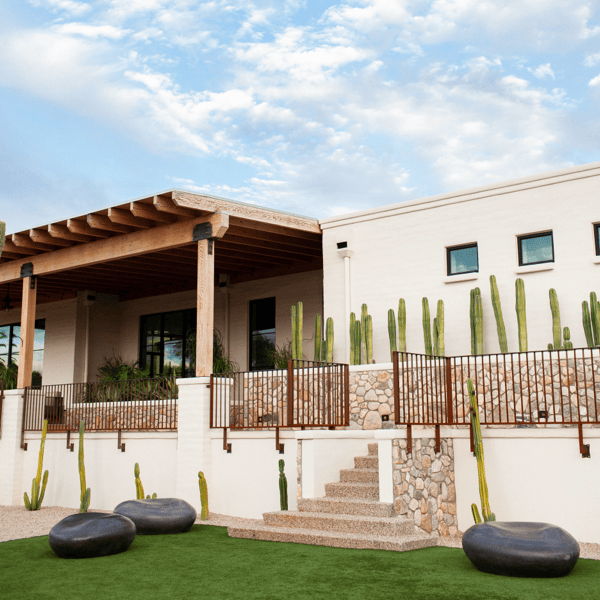 Large black outdoor pebble seats placed in a modern desert landscape with cacti, stone steps, and contemporary architecture.