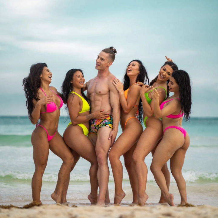 A group of people in bikinis posing at a beach