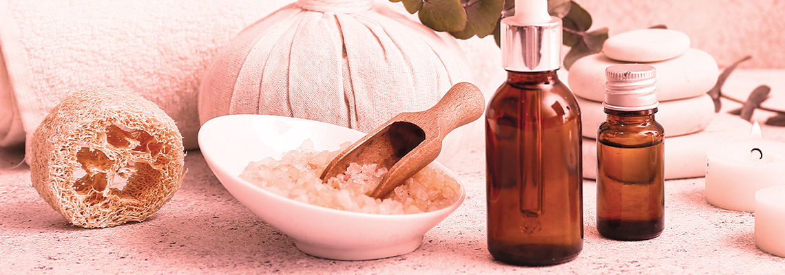 Bottles of essential oils and skincare products with a scoop and bowl.