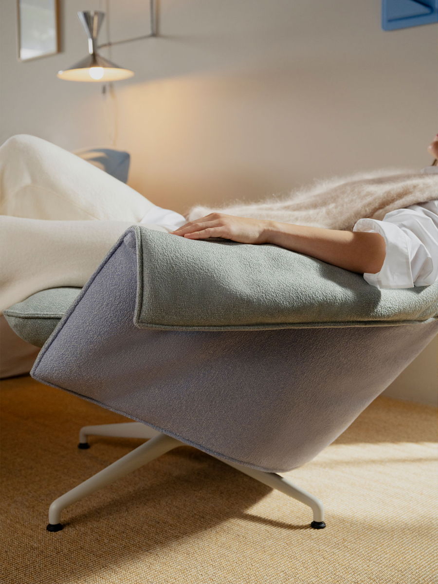 Person reclining in a Bascule chair by Vitra, wrapped in a blanket, cozy atmosphere.