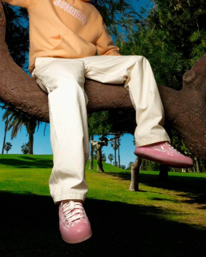 man sitting in tree wearing pink converse x golf wang shoes