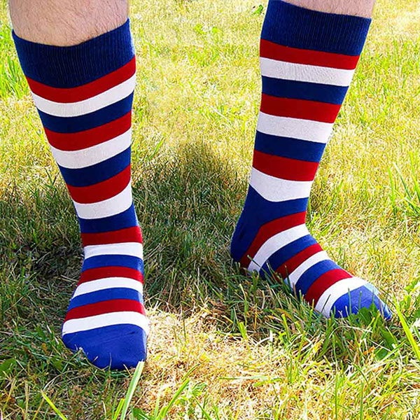 A man wearing patriotic red, white and blue striped socks outside in grass