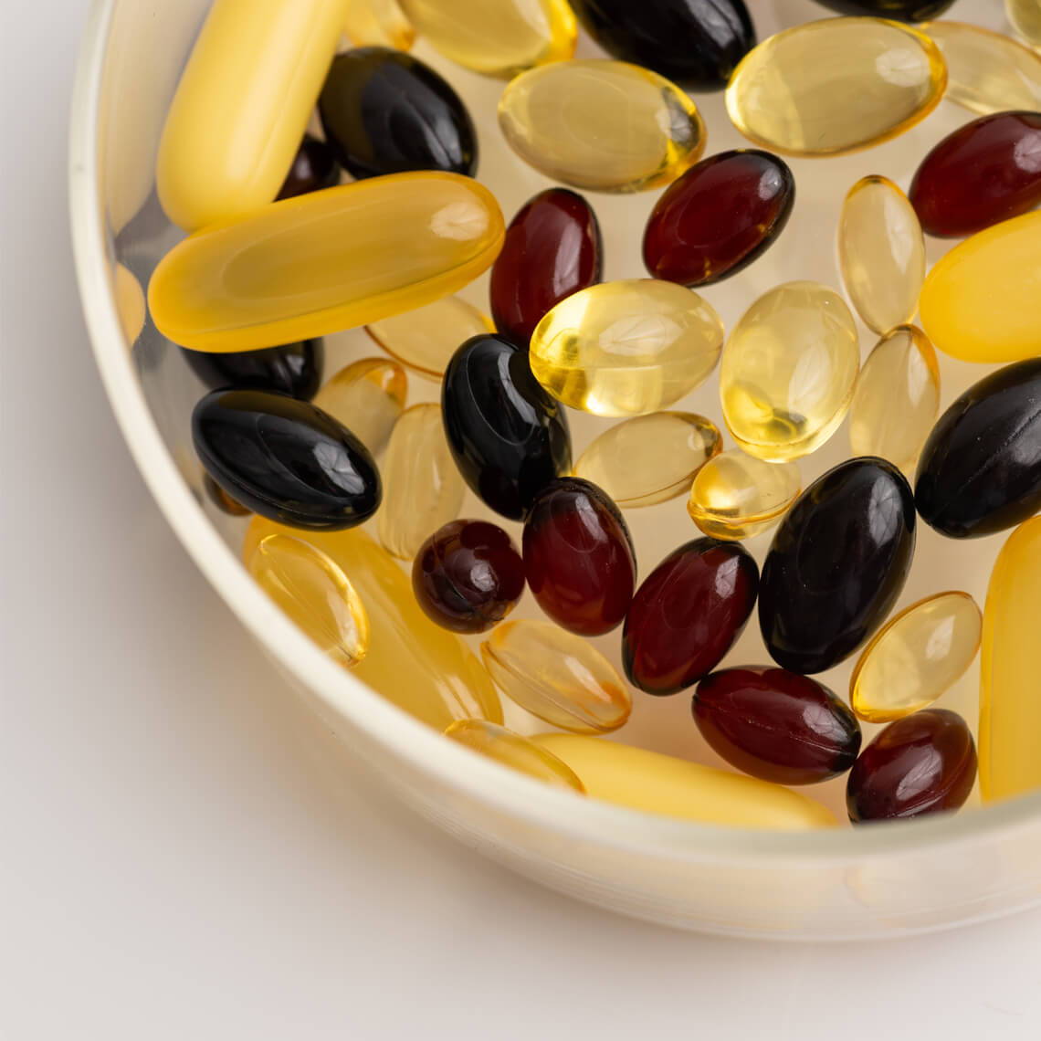A bowl filled with various colored dietary supplements and gel capsules.