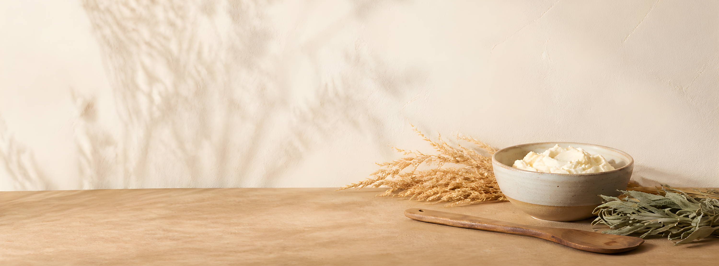 A bowl of flour with wheat and herbs on a wooden table.