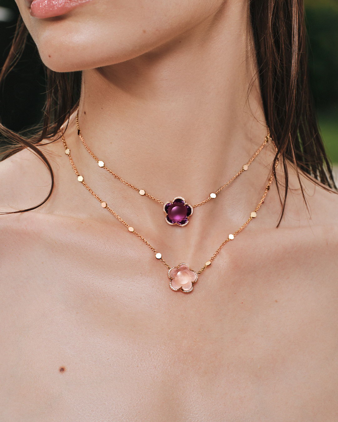 Model wearing layered necklaces with floral designs and delicate beads.