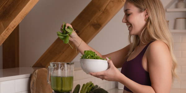 Una donna mette gli spinaci nel frullato