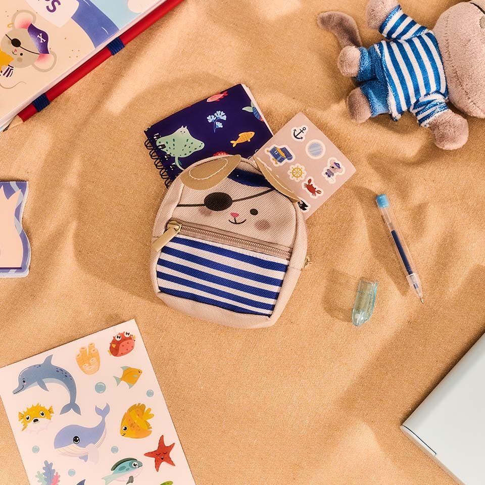 Children's pirate-themed stationery and toys on a beige surface.