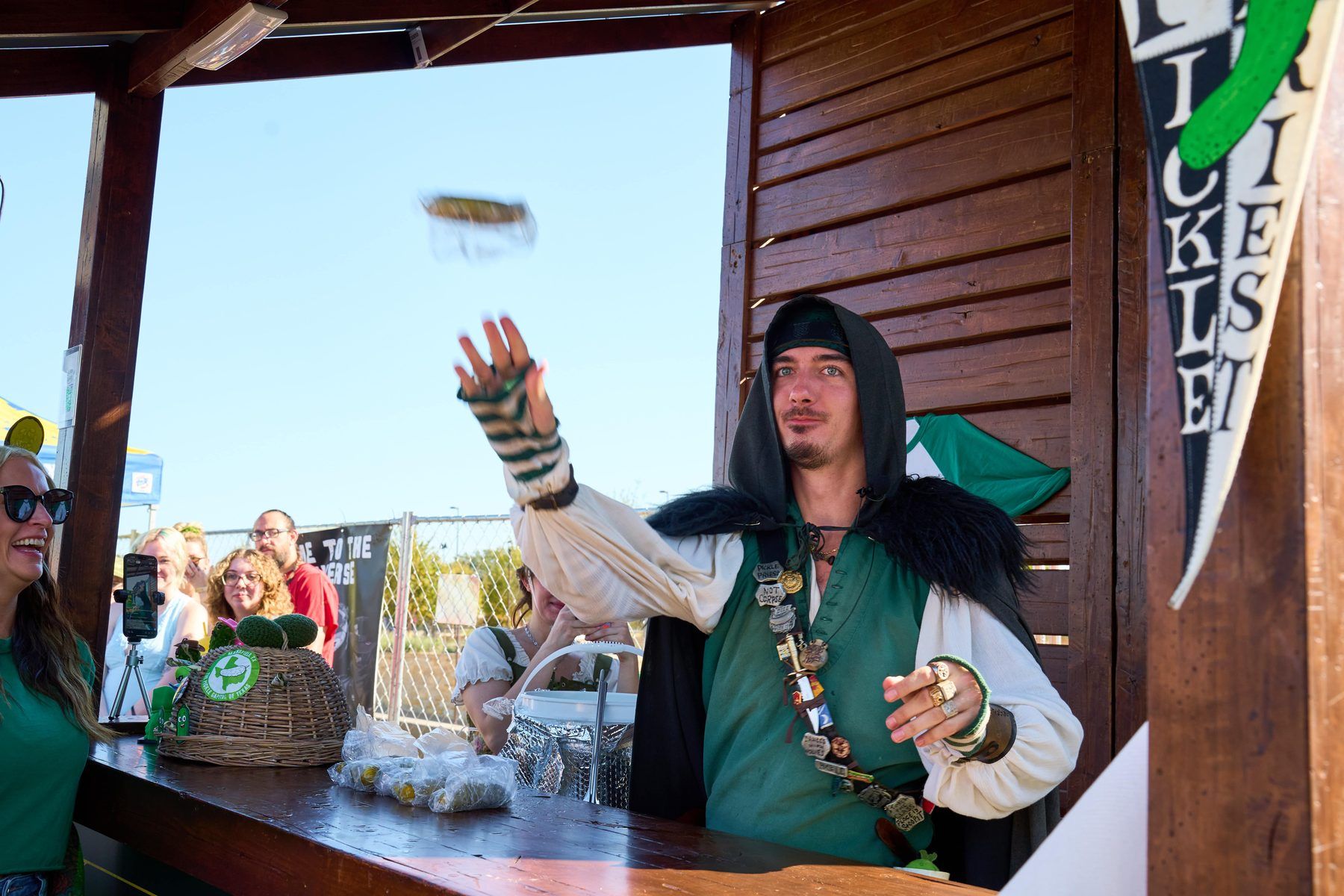The Pickle Priest Dan Castricone tossing pickles to guests in his signature green vest and hooded cloak at The Big Dill Arlington Texas 2025.