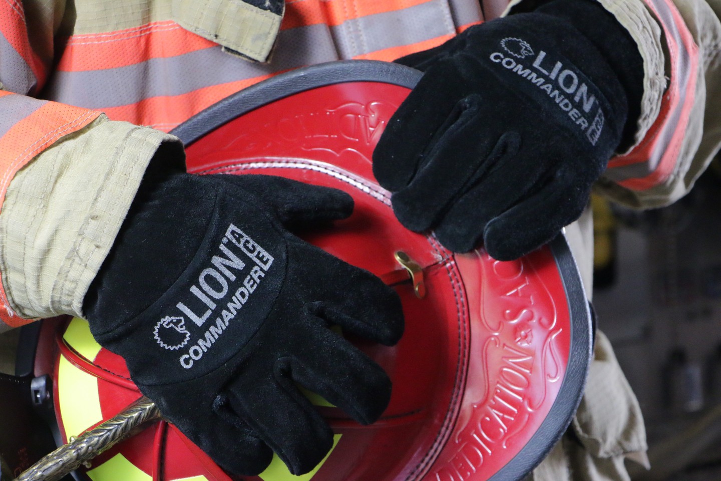Person wearing gloves, handling a red safety reel, in a work environment.