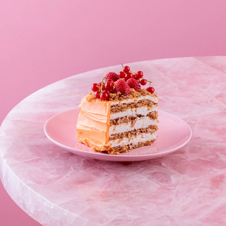 Carrot cake with orange icing and fresh berries on pink plate