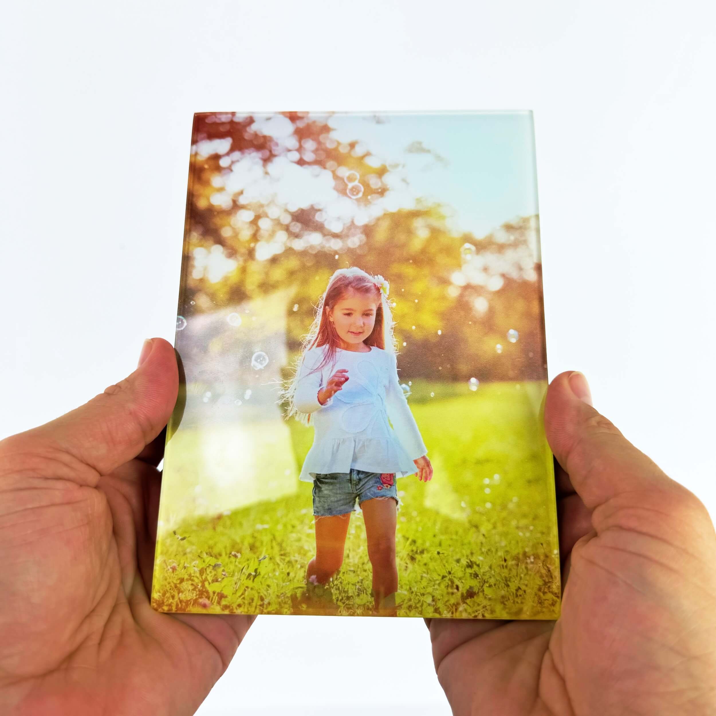 Person holding a photo of a girl in a field during sunset.