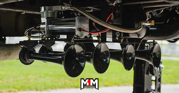 Close-up underside view of black Shocker XL train horn bells with compressor and tank mounted under Casey's 2020 Silverado 2500HD, install photo 2
