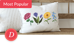 Em\mbroidered pillow with four floral designs resting on a wooden bench.