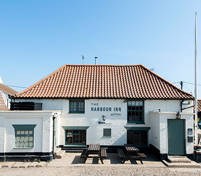 A white building with a red roof and outdoor seating area.