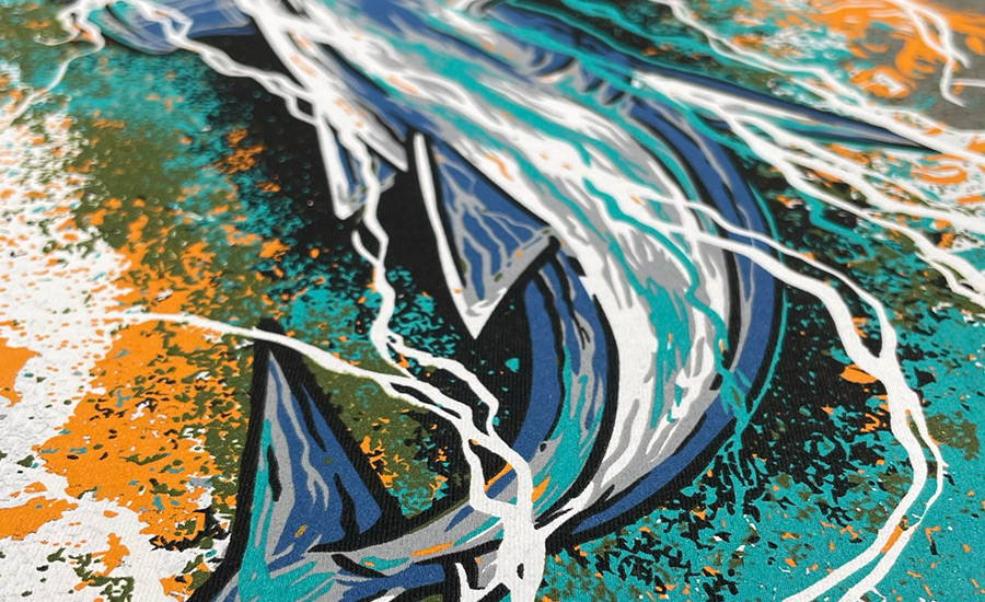 A close up image of a spot colour screen printed design of a hammerhead shark in blue, aquamarine, light grey and white with yellow, army green, and black distressed textured background and line detail in white and aqua in the foreground representing rippling water.