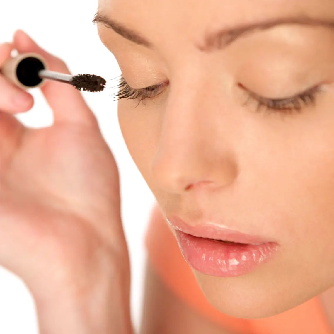 Woman applying mascara to her eyelashes.