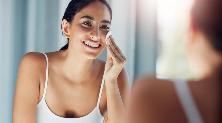 woman removing her makeup in mirror
