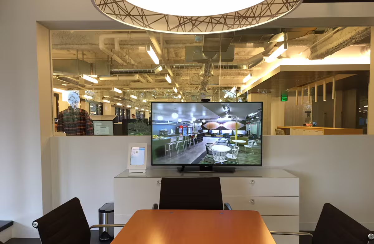 Modern office space with a large TV screen and a conference table.