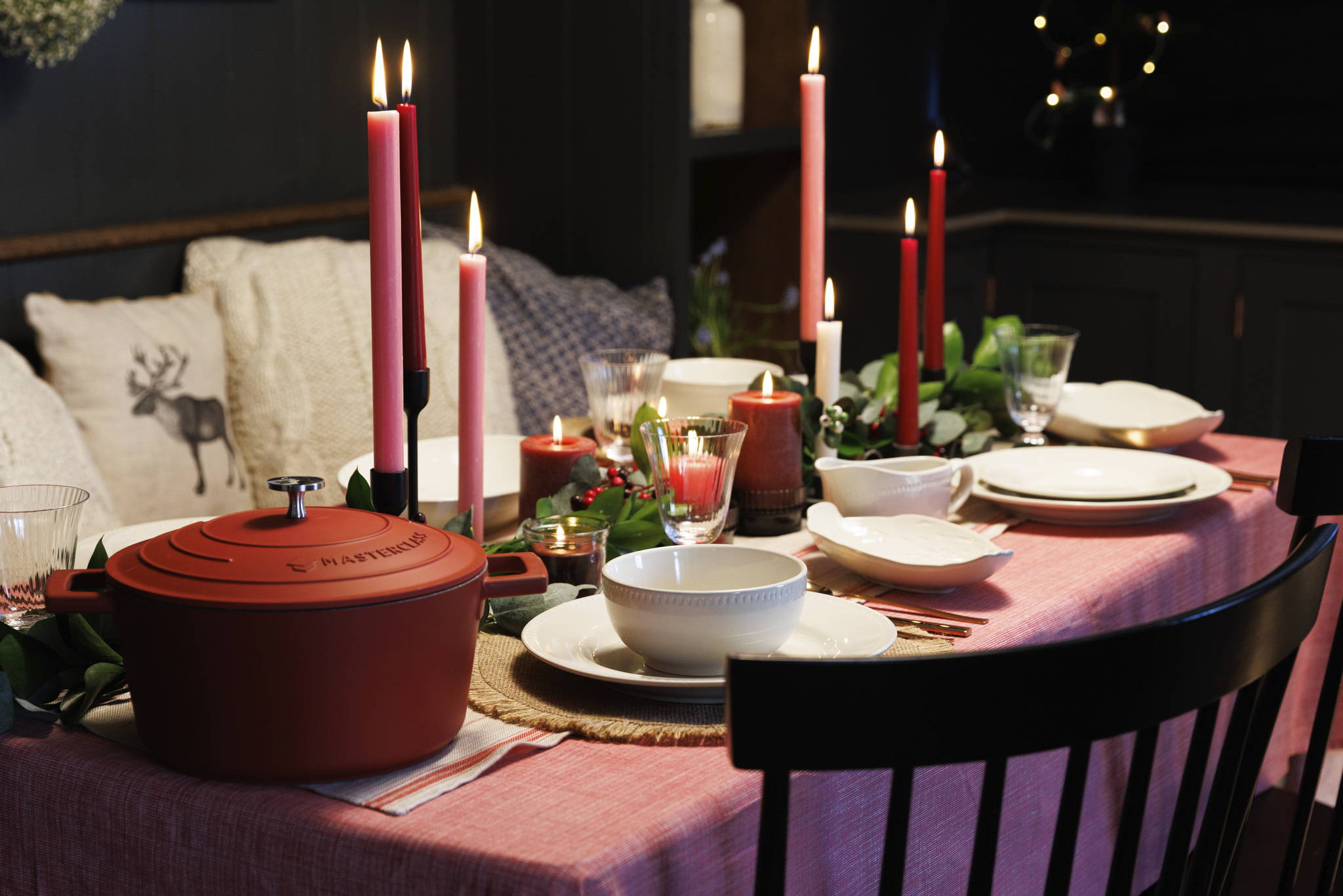 A set dining table decorated with candles and holly.
