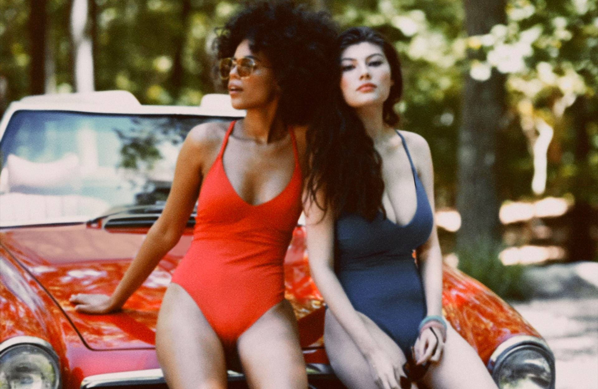 Two models wearing cosabella one piece swimsuits.