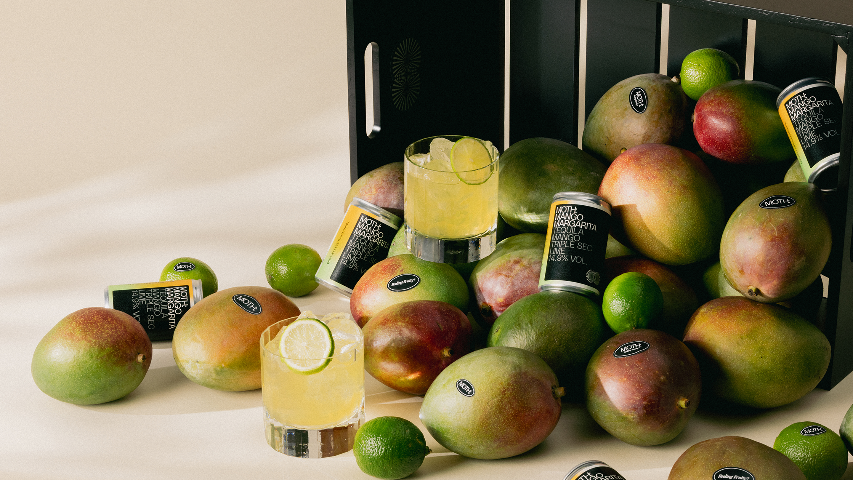 A pile of mangoes and drinks, with limes scattered around.