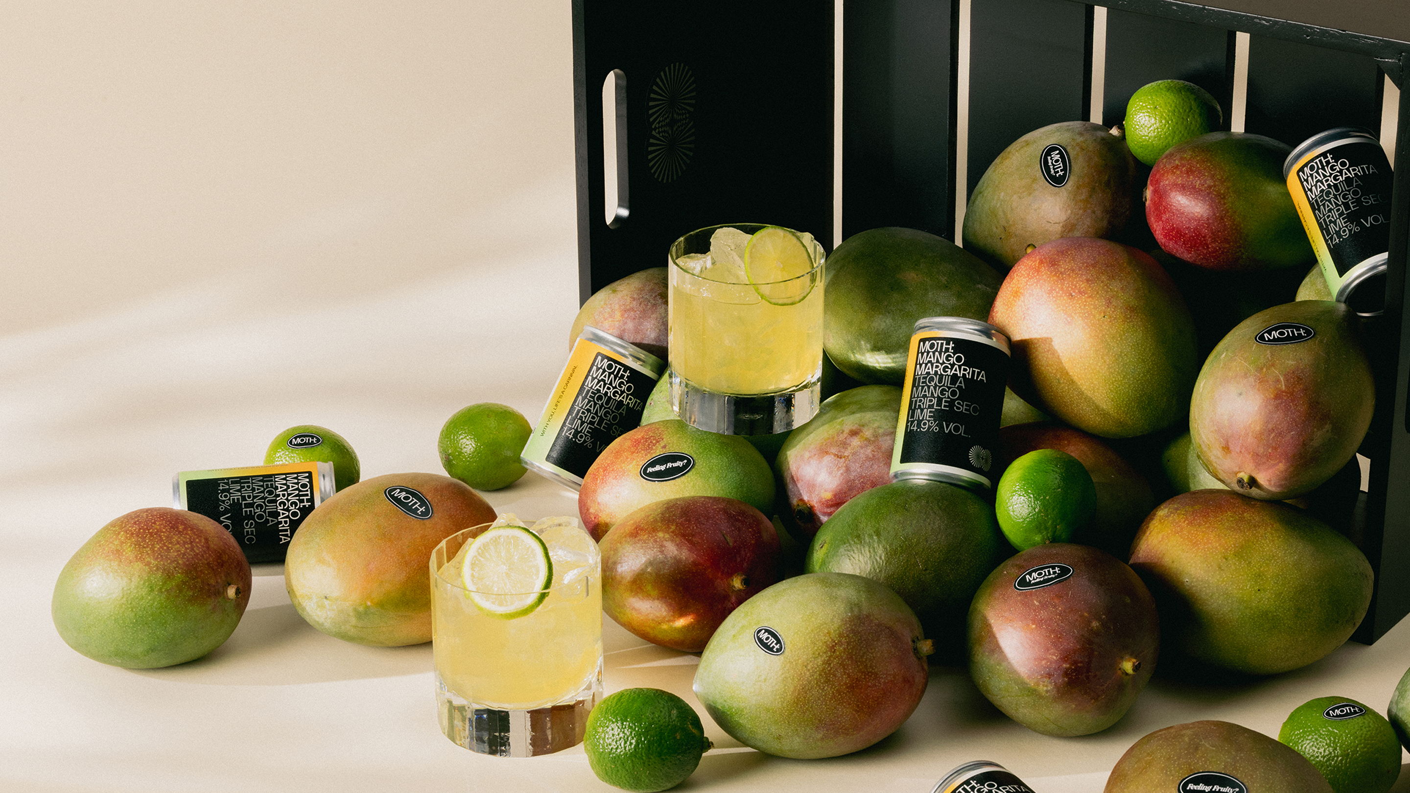 A pile of mangoes and drinks, with limes scattered around.