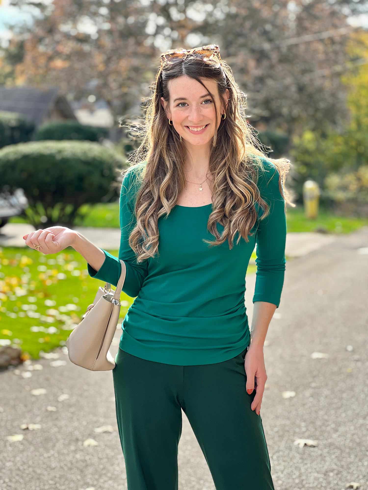 Woman standing wearing Miik's Akari side ruched reversible top in green with matching pants