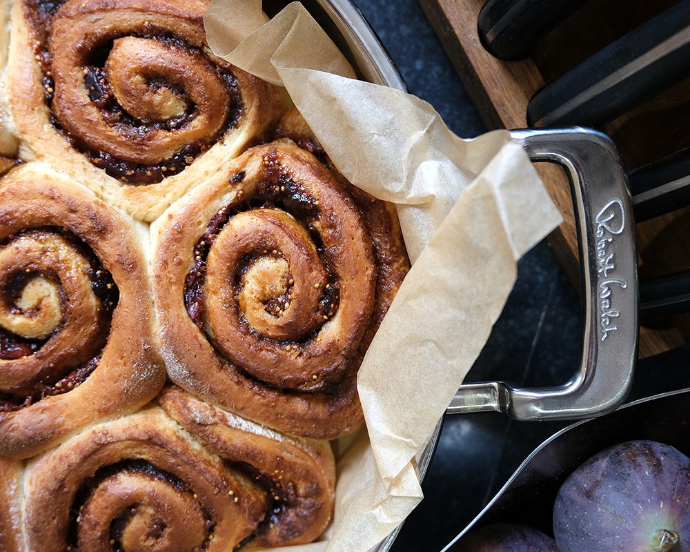 Cinnamon rolls in a baking dish with parchment paper.