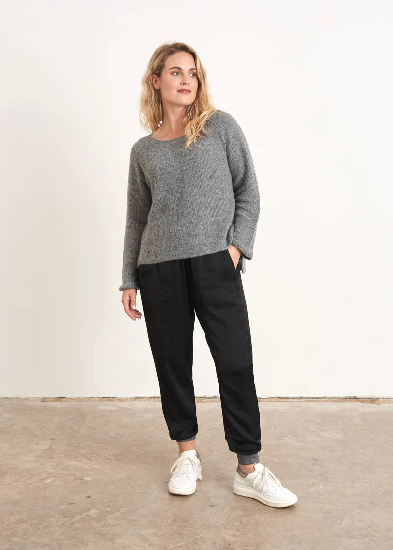 A model wearing a GREY boxy knitted sweater with black trousers and white trainers