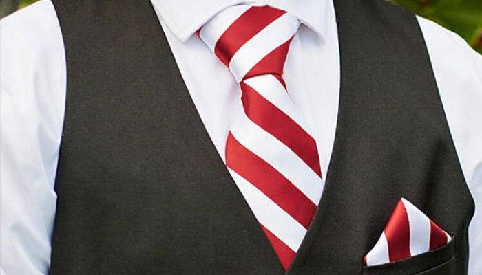 Man wearing red and white striped necktie and pocket square set with black vest